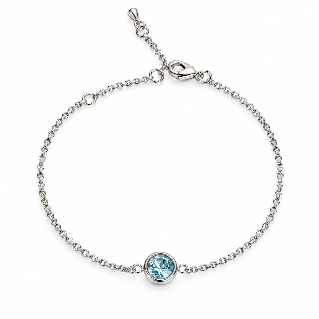 A delicate silver chain finish bracelet with a single bezel-set light blue gemstone, displayed on a clean, light pink background.